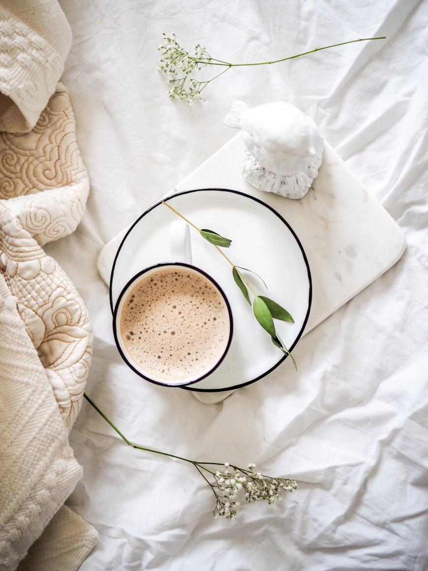 A frothy hot chocolate in an enamel mug on a marble board, dressed with gypsophila